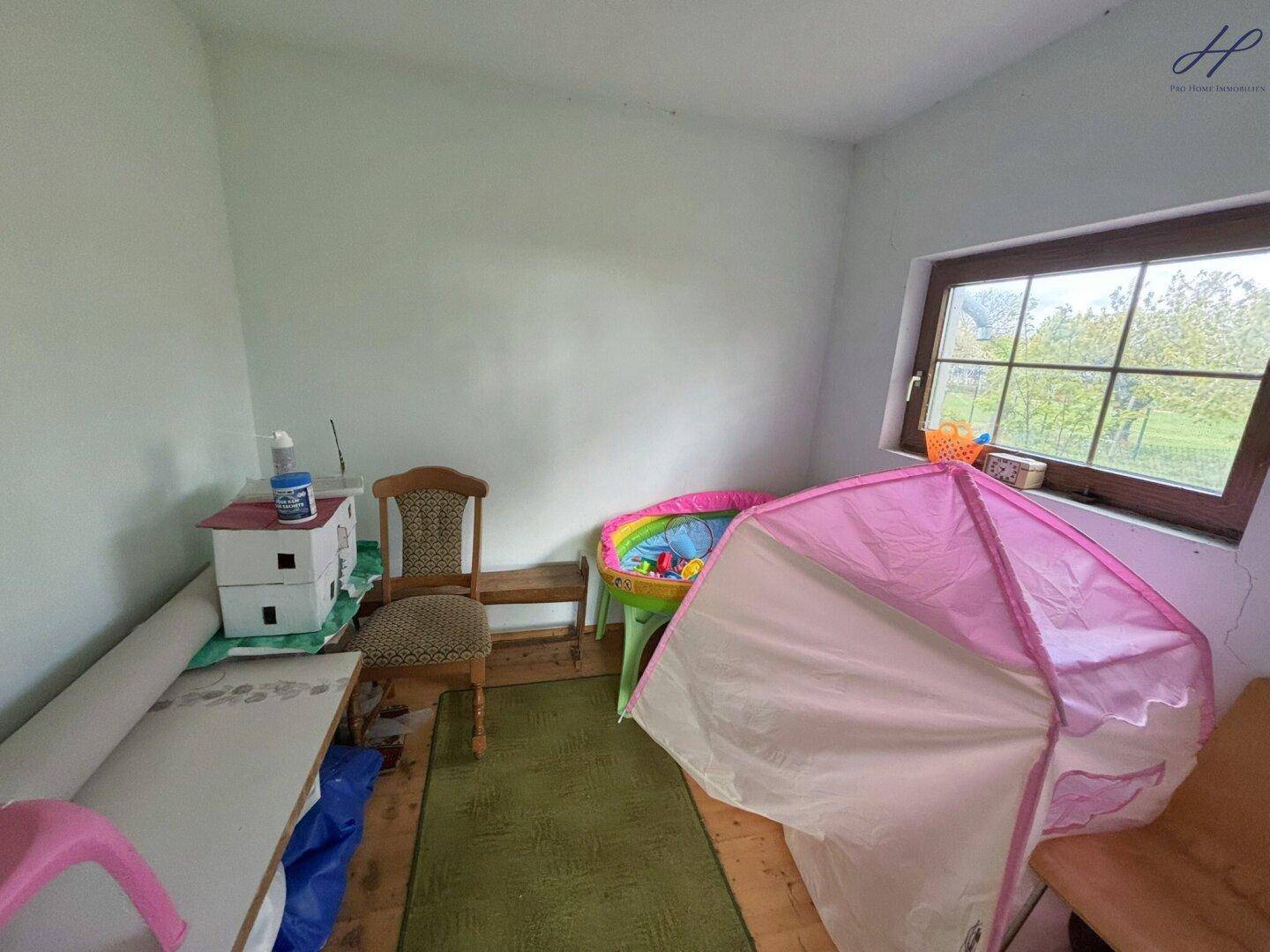 Kleiner Raum mit Fenster und Spielzeug, möglicherweise als Abstellraum oder Kinderzimmer genutzt.