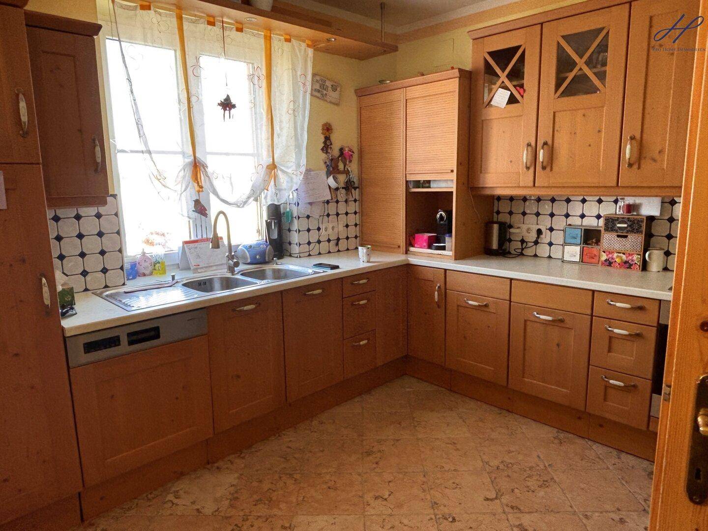 Funktionale Küche mit Holzschränken, Fliesenrückwand und Doppelspüle.