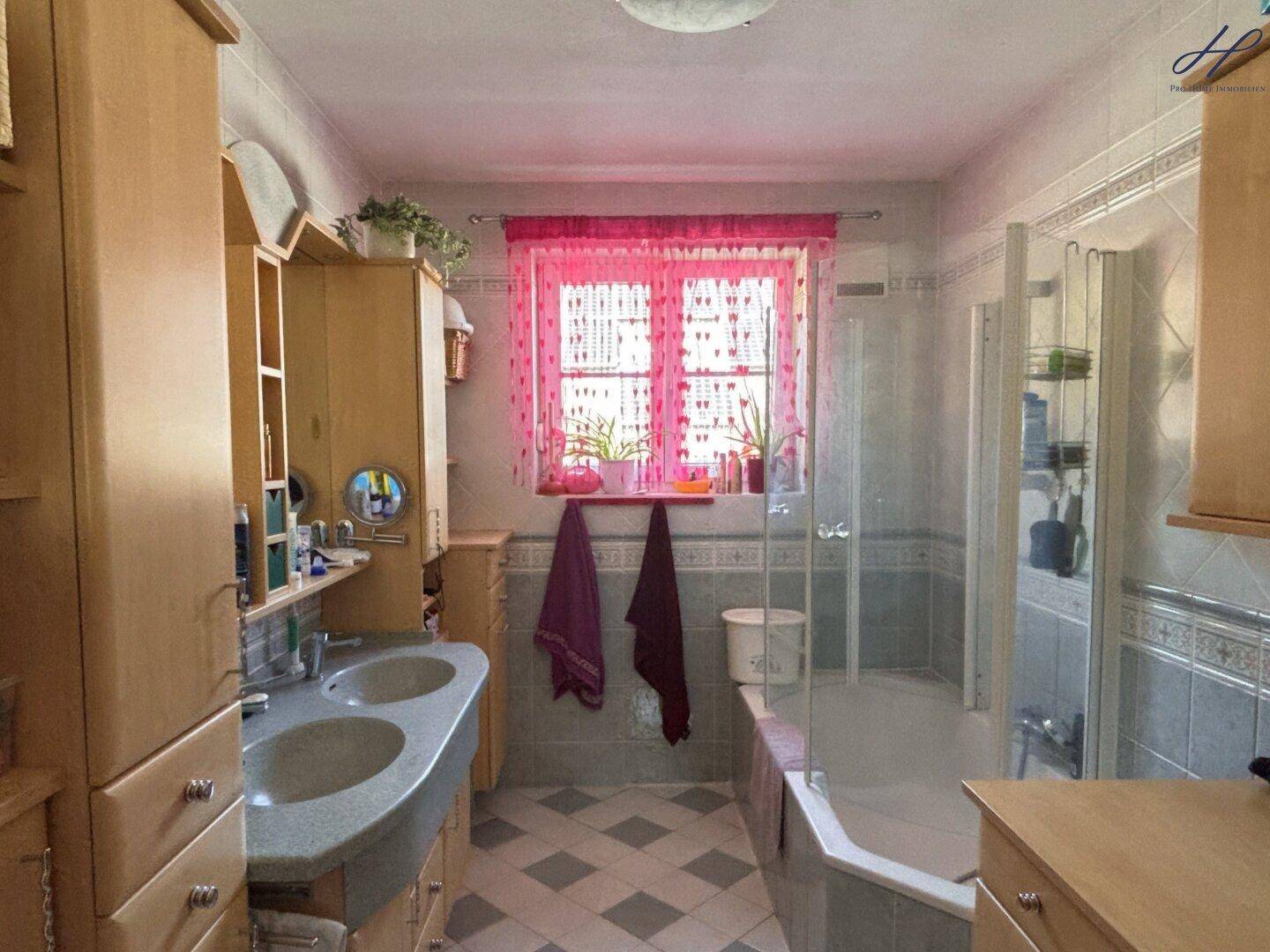 Badezimmer mit Doppelwaschbecken, Badewanne und Dusche, dekoriert in Rosa.