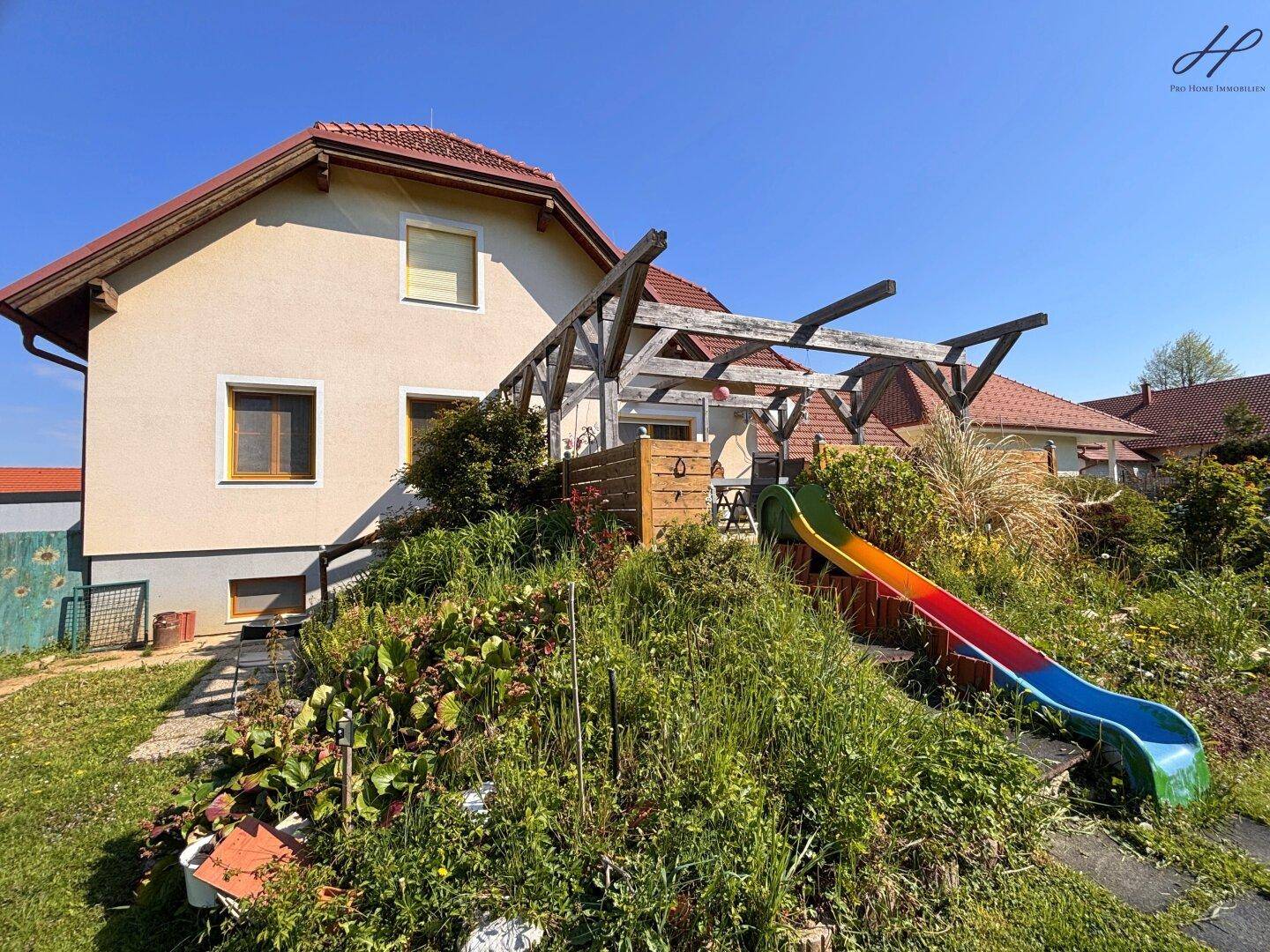 Großer Gartenbereich mit Rutsche und üppiger Vegetation am Hang.