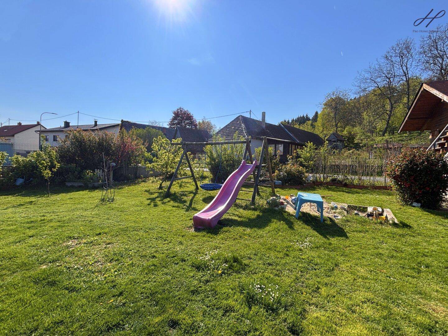 Sonniger Garten mit Schaukel, Sandkasten und viel Platz zum Spielen.