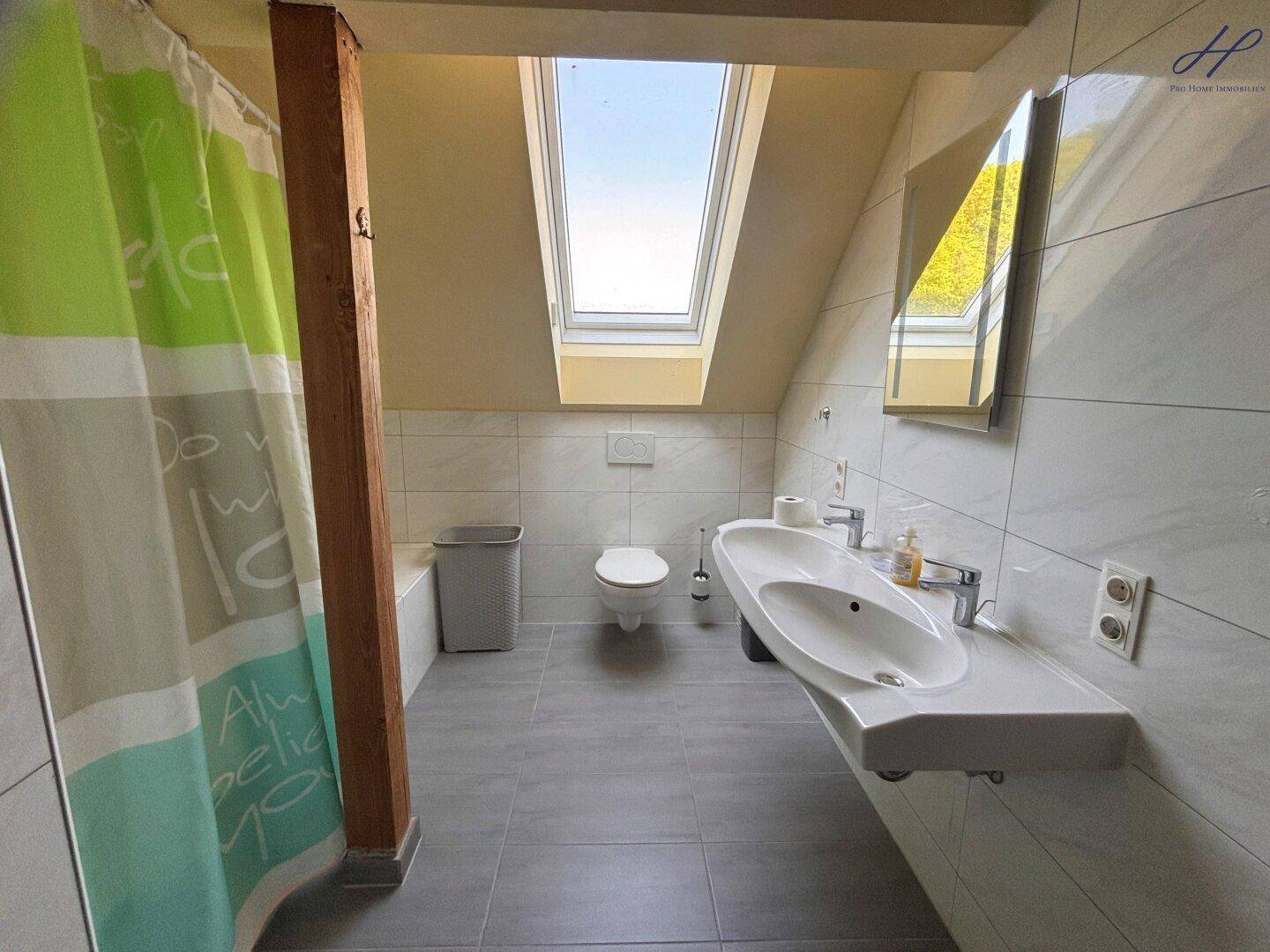 Modernisiertes Badezimmer im Dachgeschoss mit Dachfenster, Dusche und Hänge-WC.
