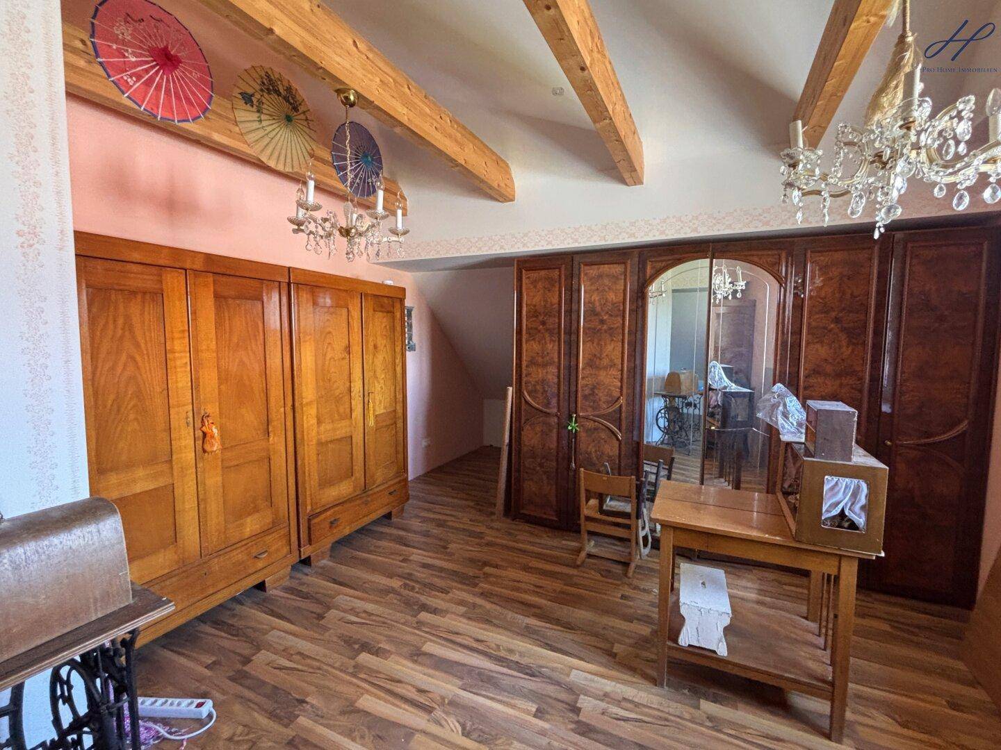 Schlafzimmer im Landhausstil mit antiken Holzschränken, freiliegenden Holzbalken und Kronleuchtern.
