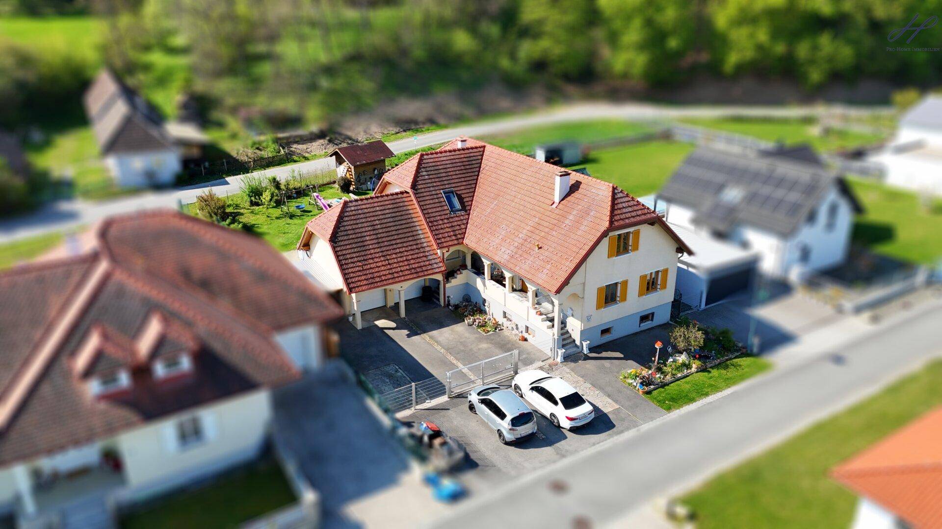 Luftaufnahme des Hauses mit gepflegter Auffahrt und umliegender Wohngegend an einem sonnigen Tag.