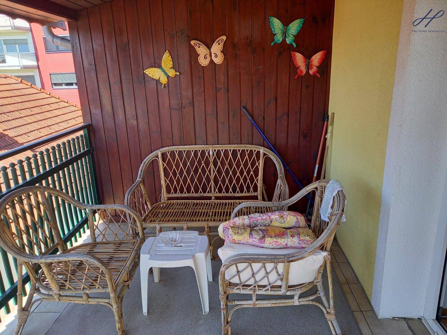 Gemütlicher Balkon mit Korbmöbeln und Holzwänden, ideal zum Entspannen.