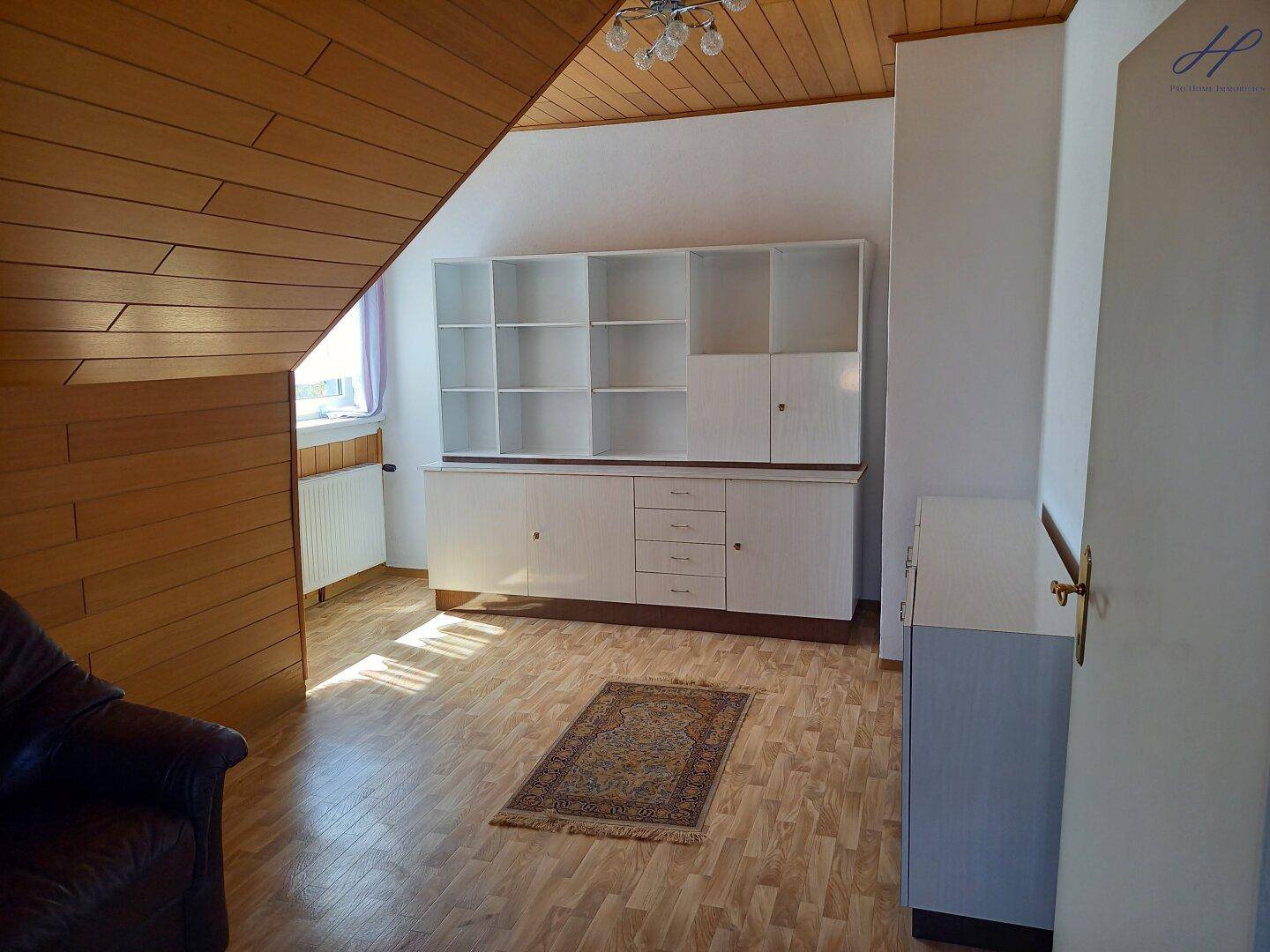Dachgeschosszimmer mit Holzdecke, Laminatboden und großem Einbauschrank.