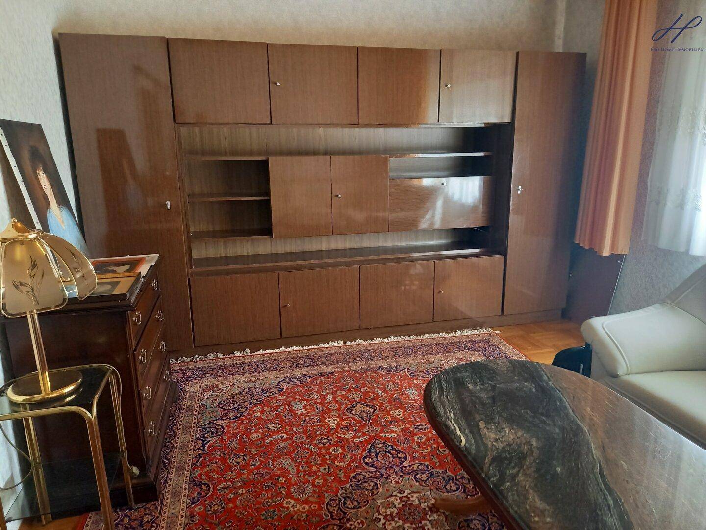 Geräumiges Wohnzimmer mit dunklem Holzschrank, Teppich und traditioneller Einrichtung.