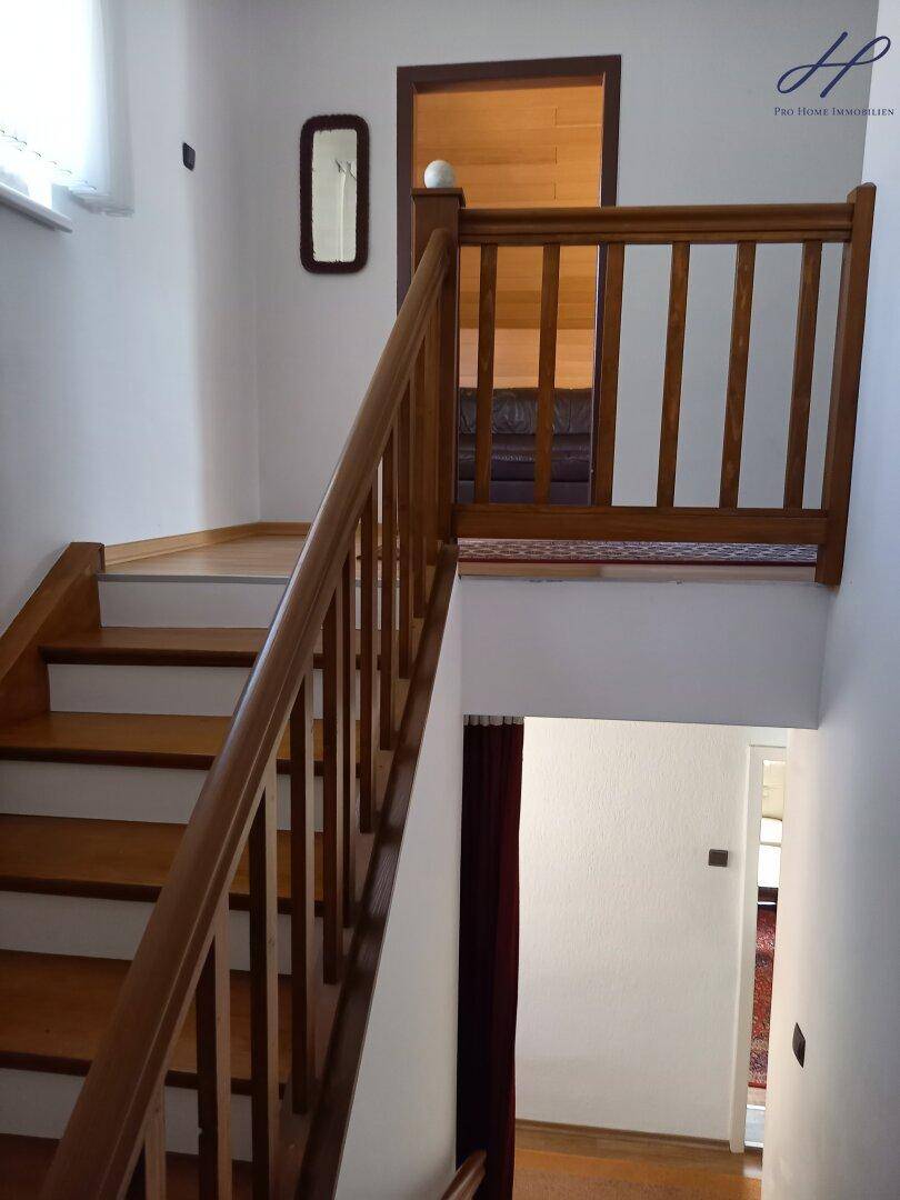 Holztreppe mit Geländer, die die verschiedenen Etagen des Hauses verbindet.