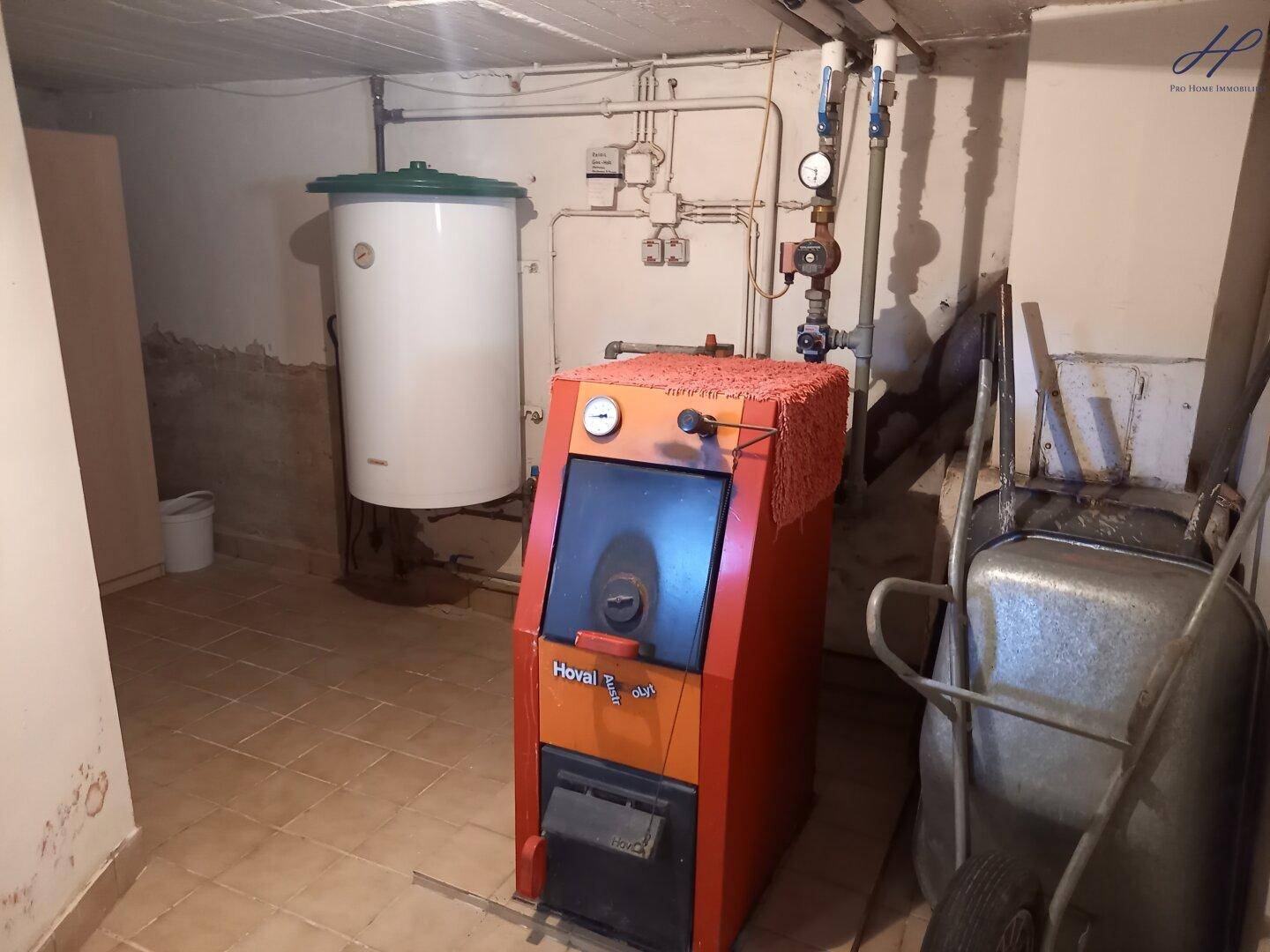 Heizungsraum im Keller mit großem Warmwasserspeicher und Holzofen.