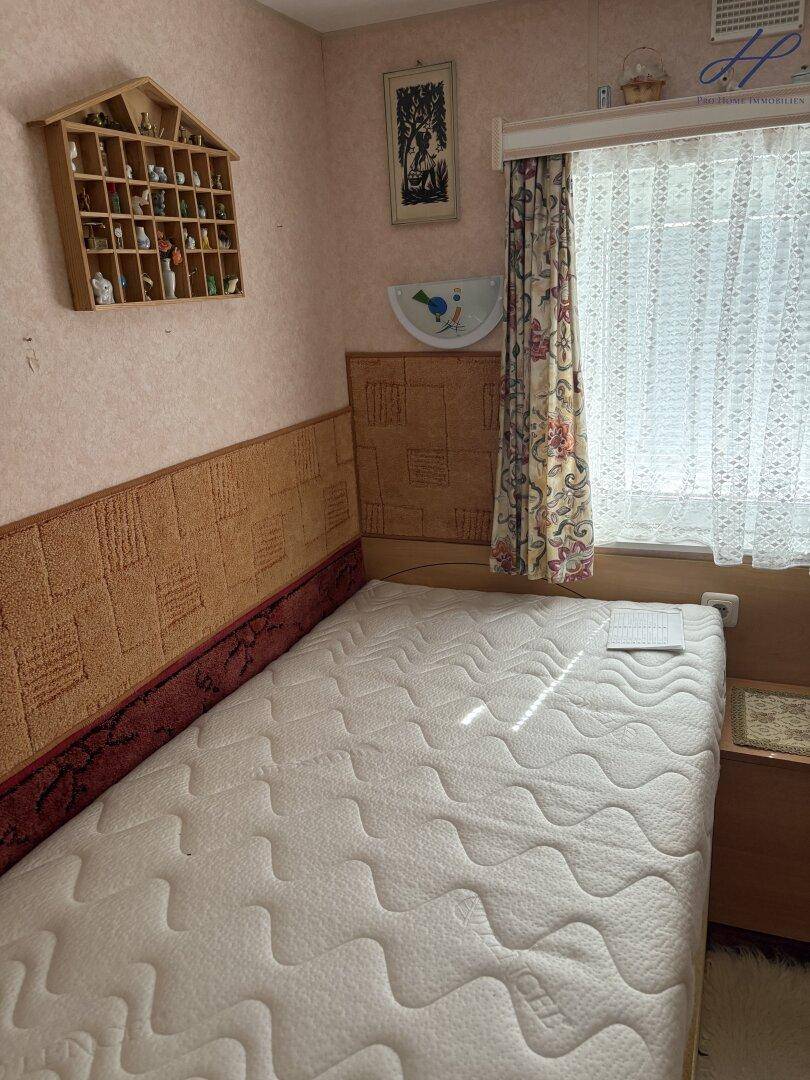 Schlafzimmer mit Einzelbett, Nachttisch und dekorativer Wandgestaltung in Pastellfarben.