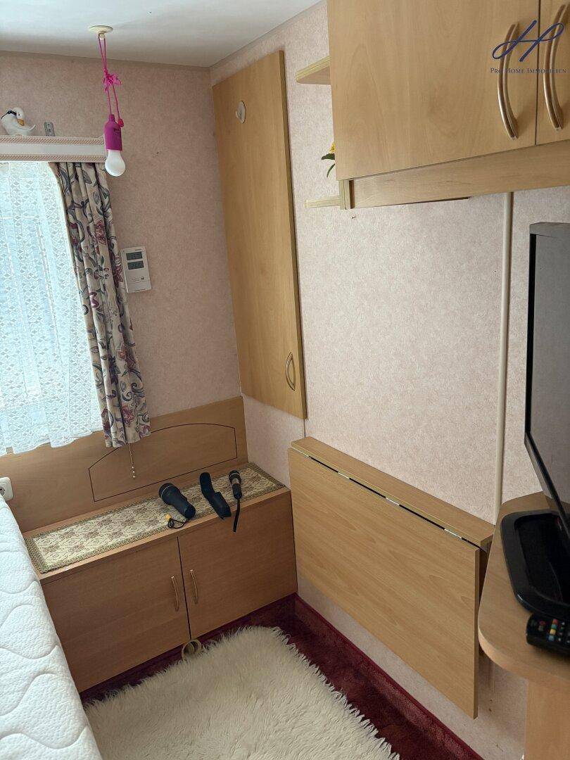 Schlafzimmer mit Bett, Einbauschränken und einem ausklappbaren Tisch für zusätzlichen Platz.
