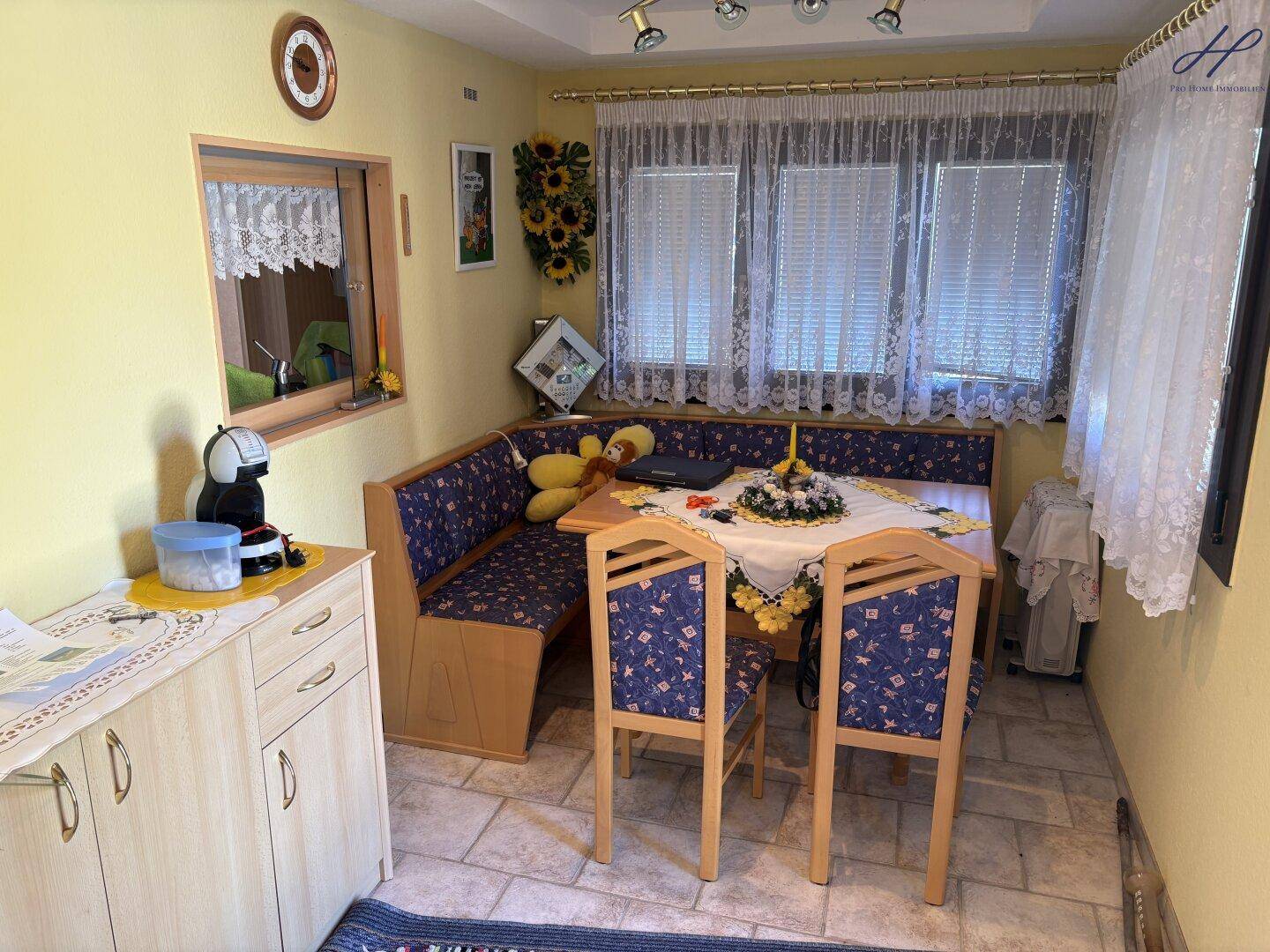 Gemütlicher Essbereich mit Eckbank, Holztisch und Fliesenboden in warmer Farbgebung.