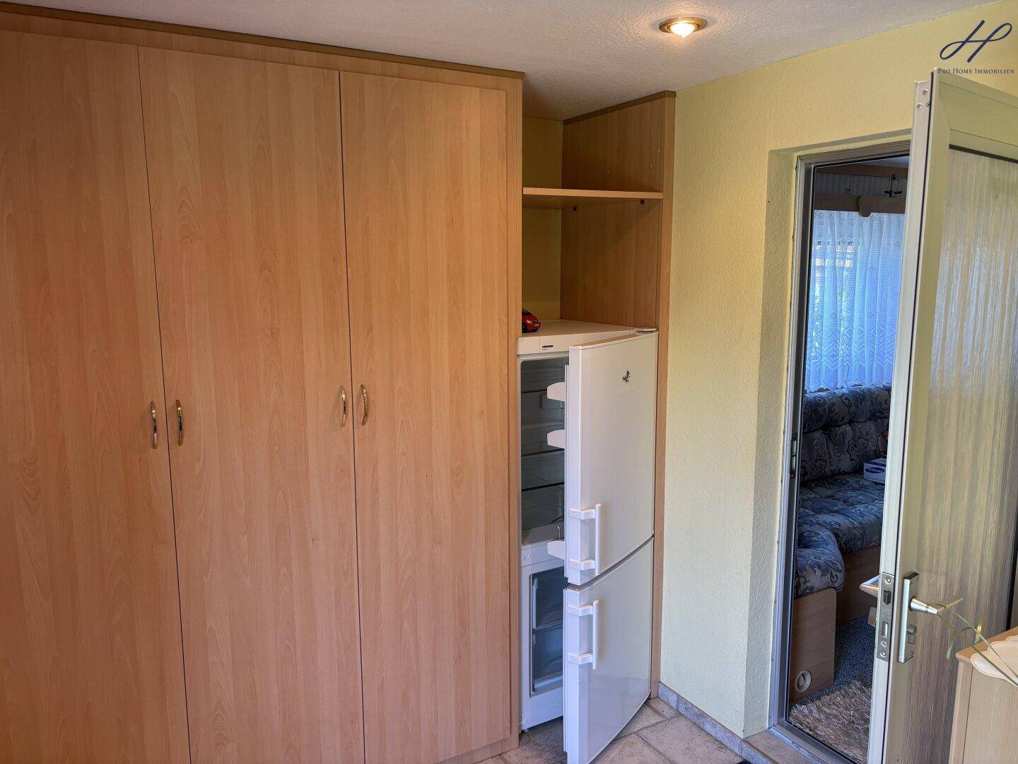 Flur mit großem Kleiderschrank und integriertem Kühlschrank, der zum Wohnbereich führt.