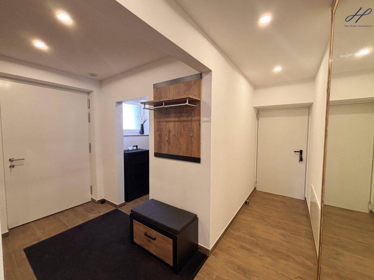 Moderner Flur mit Garderobe, Sitzbank und hellem Boden, der zu weiteren Räumen führt.