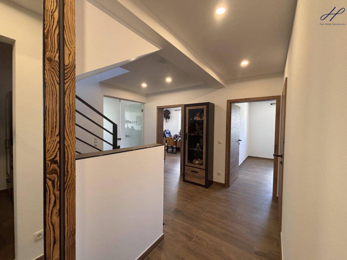 Geräumiger Flur mit Holzfußboden, Einbauschränken und Blick auf die Treppe und weitere Zimmer.