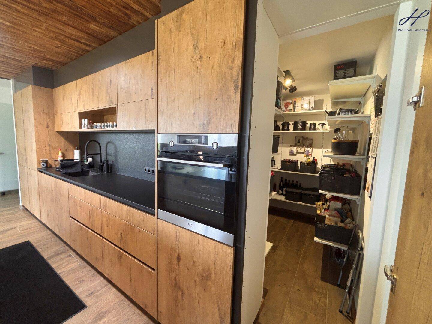 Moderne Holzküche mit integrierten Geräten und direktem Zugang zu einer praktischen Speisekammer.