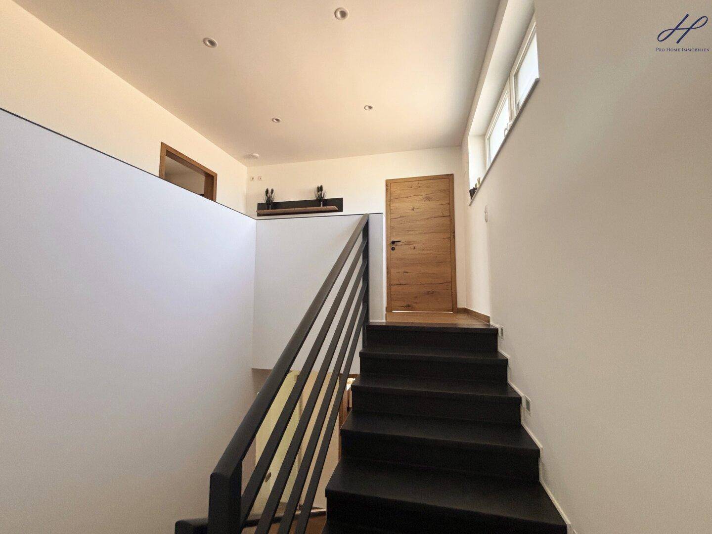 Moderne Treppe mit dunklen Stufen und Geländer, die zu den oberen Etagen führt.