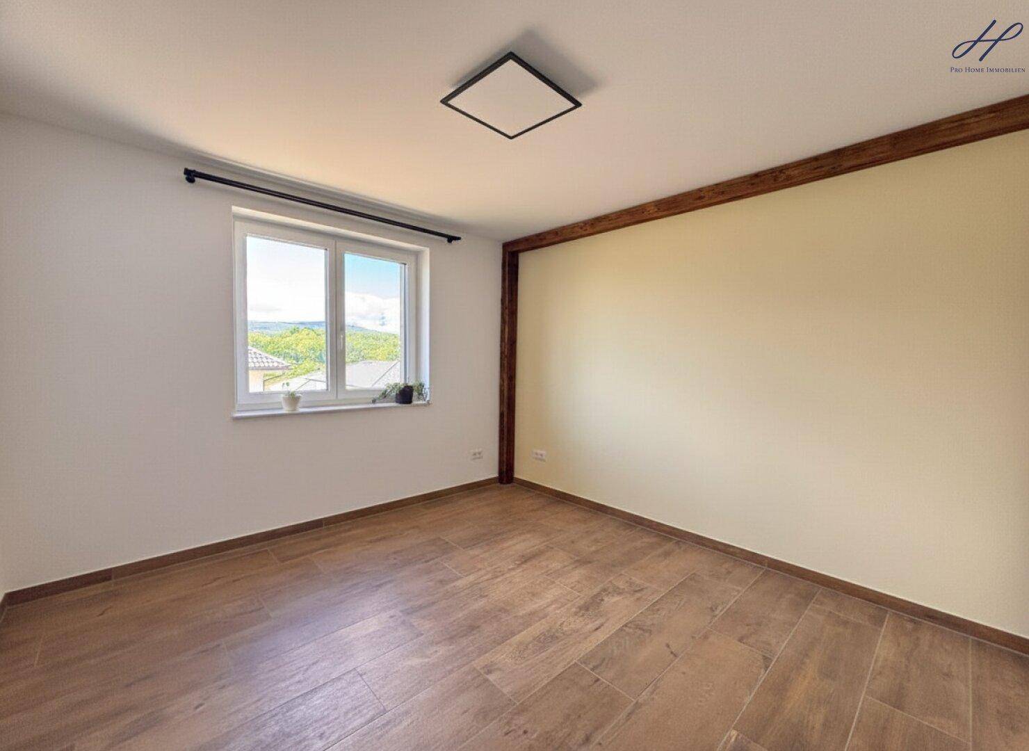 Helles Schlafzimmer mit Holzbalken, Fliesenboden und Fenster mit Blick auf die Landschaft.