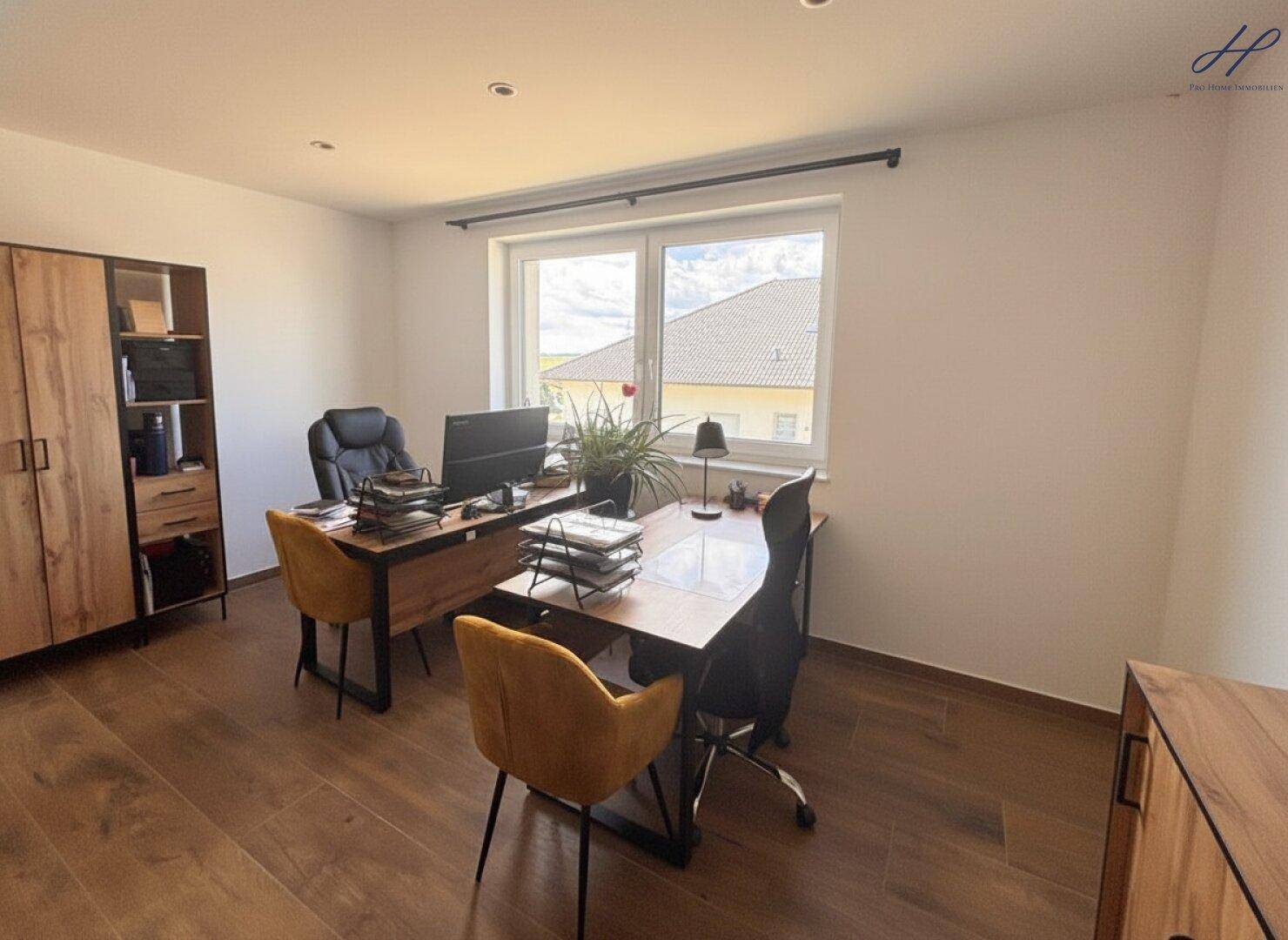 Geräumiges Arbeitszimmer mit zwei Schreibtischen, Holzmöbeln und Blick ins Grüne.