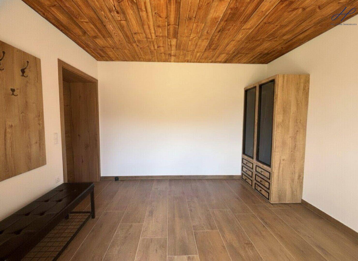 Geräumiges Zimmer mit Holzdecke, Fliesenboden und modernem Schrank.