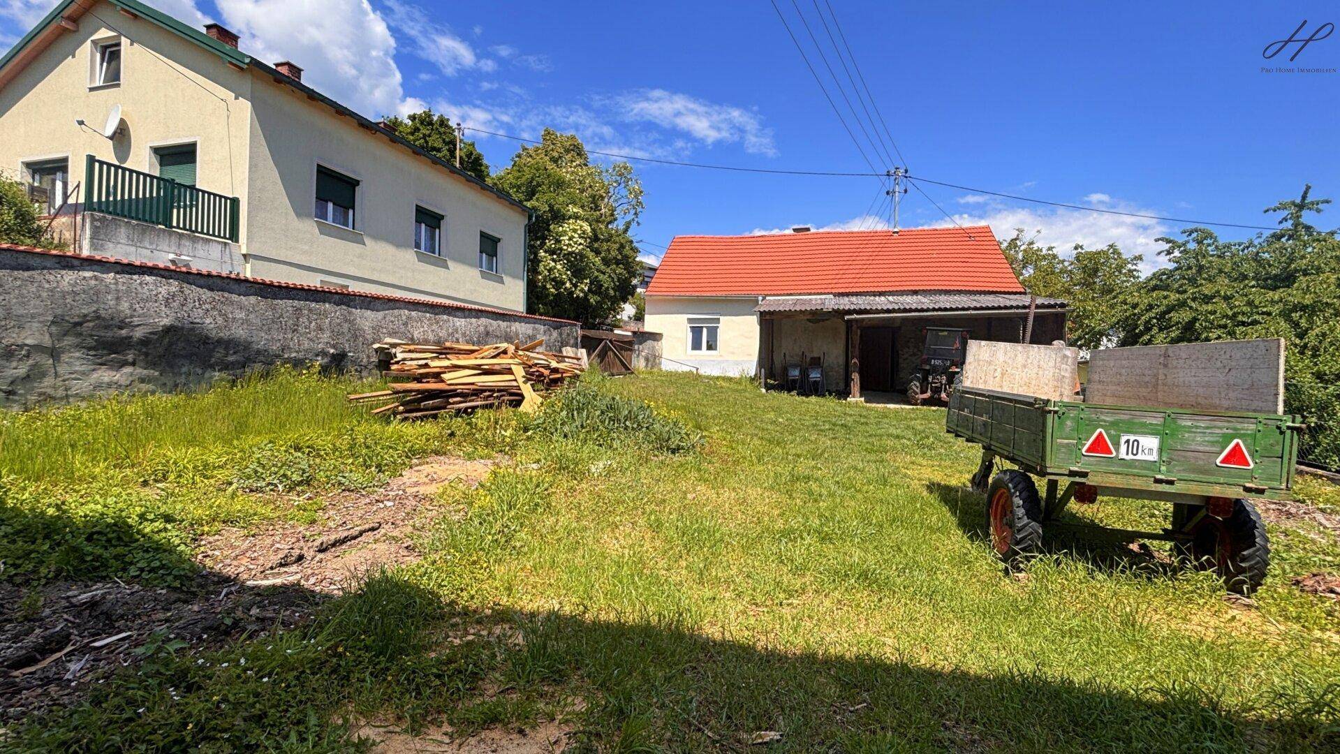 Großer Gartenbereich mit einem Anhänger und Blick auf das ländliche Haus und die Umgebung.