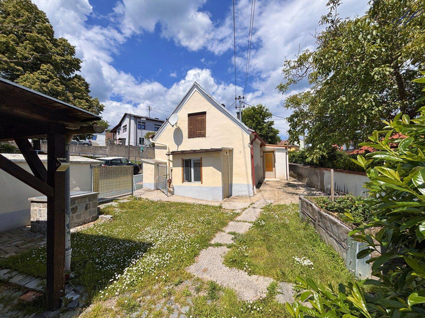 Gartenansicht des Hauses mit Rasenfläche, gepflastertem Weg und Blick auf die ländliche Umgebung.