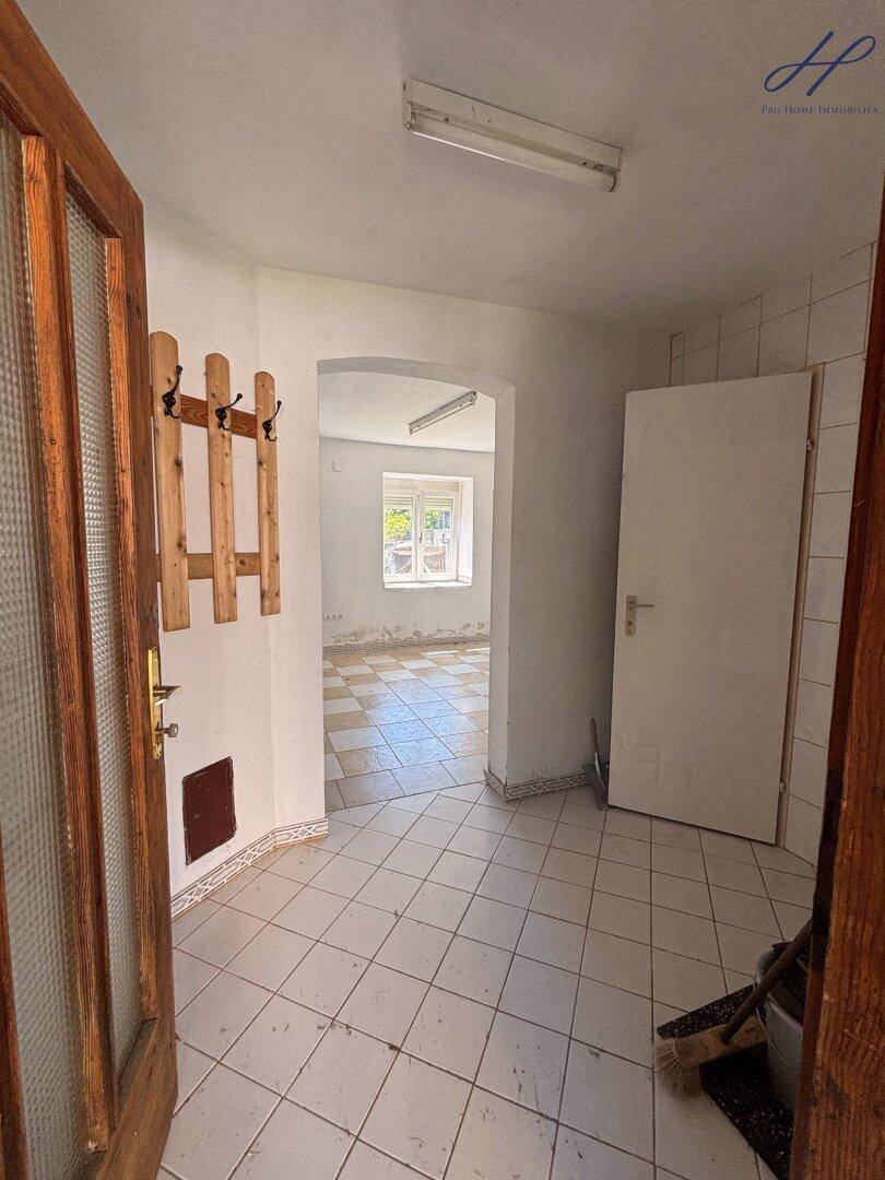 Eingangsbereich mit Fliesenboden, Garderobe und Blick in einen angrenzenden Raum.