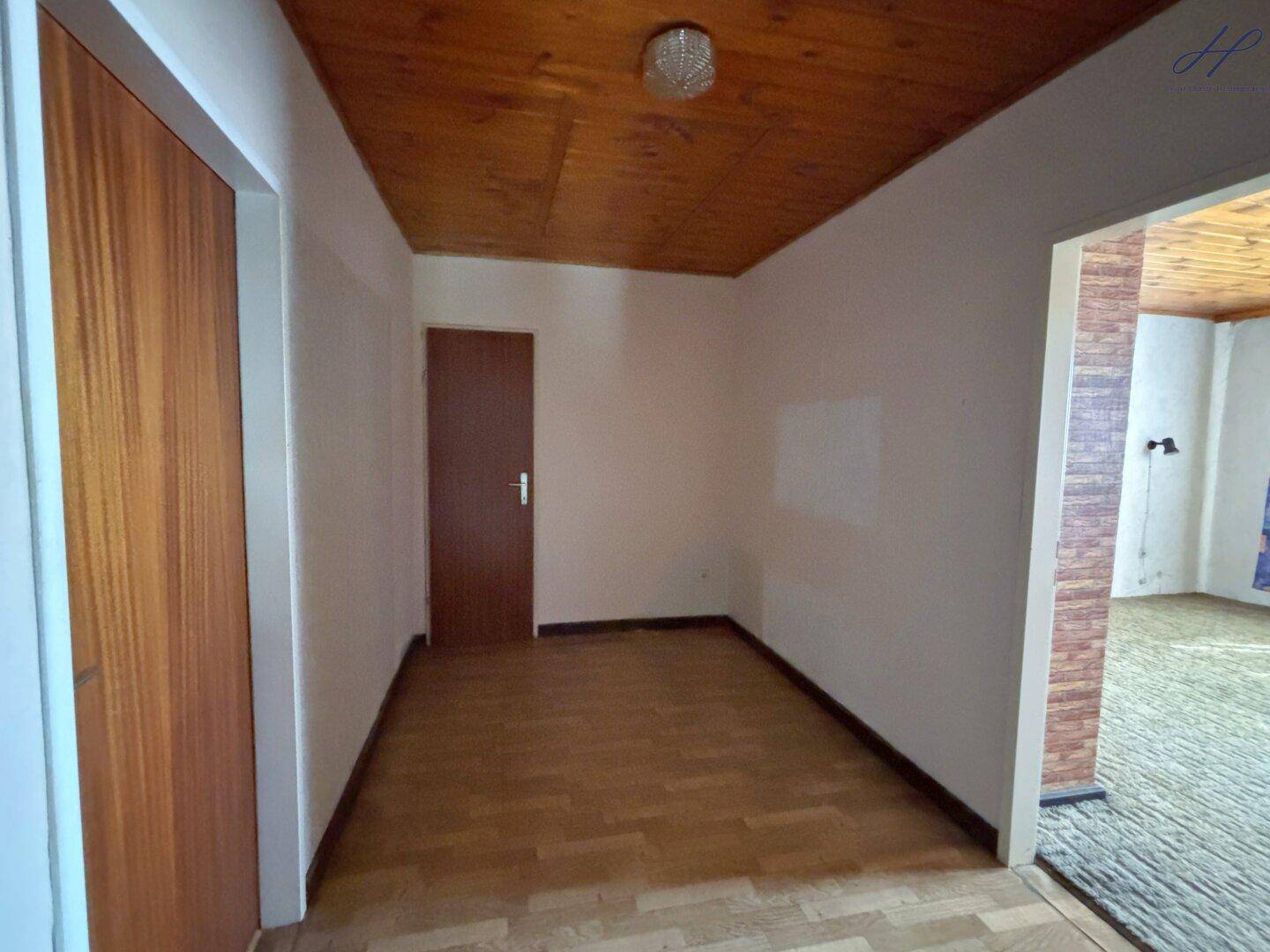 Heller Flur mit Holzdecke und Laminatboden, der zu weiteren Räumen führt.