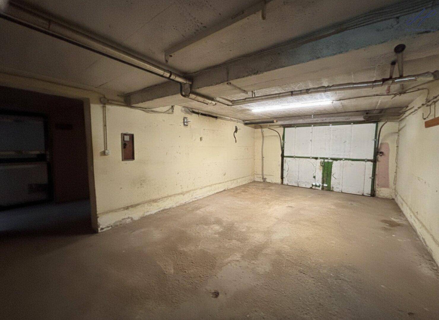 Geräumige Garage mit Betonboden und Rolltor, bietet Platz für Fahrzeuge und Lagerung.