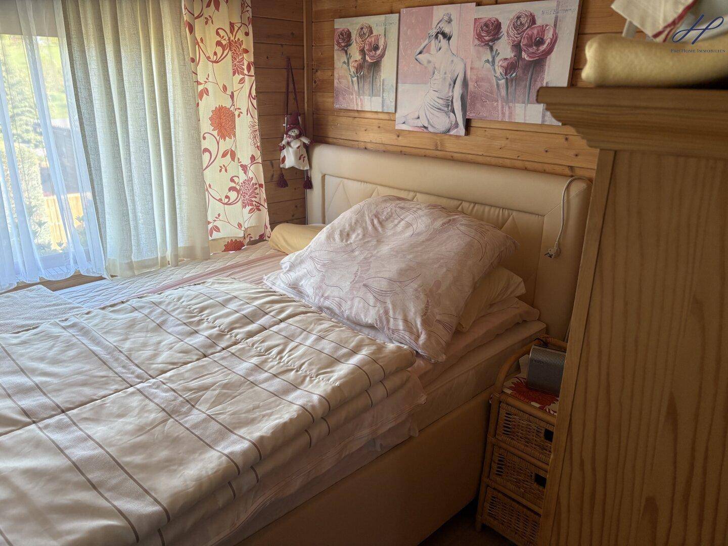Helles Schlafzimmer mit Doppelbett, Holzvertäfelung und floralen Vorhängen, bietet eine gemütliche Atmosphäre.