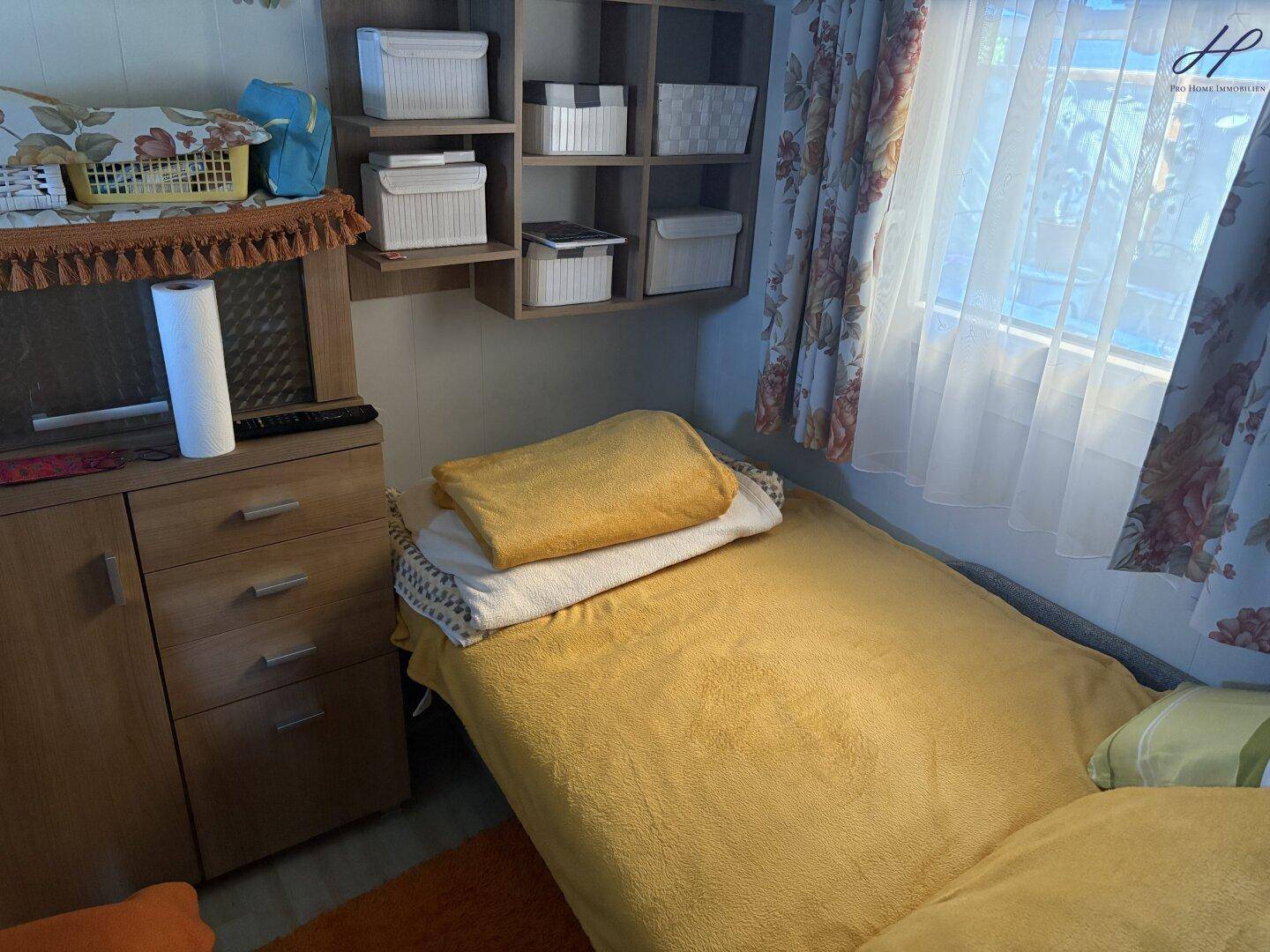 Kleines Schlafzimmer mit Einzelbett, Holzmöbeln und Fenster, bietet eine ruhige Rückzugsmöglichkeit.