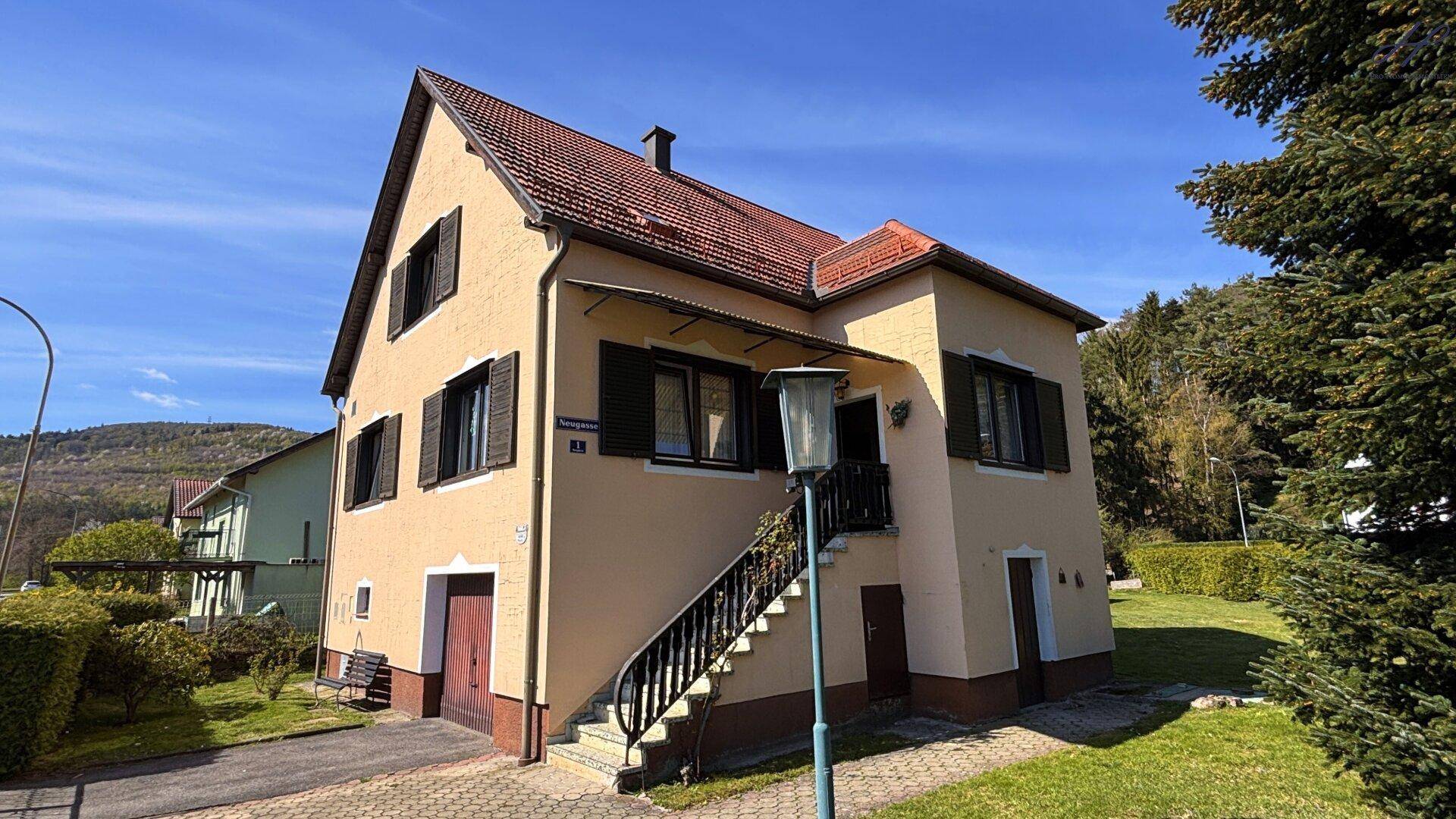 Vorderansicht des Hauses an einem sonnigen Tag mit Außentreppe und gepflegtem Vorgarten.