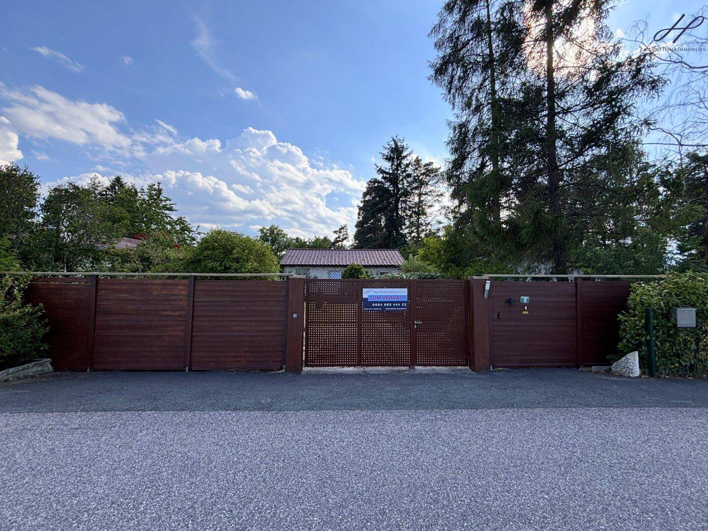 Eingangstor zum Grundstück von der Straße aus, mit einem Verkaufsschild.