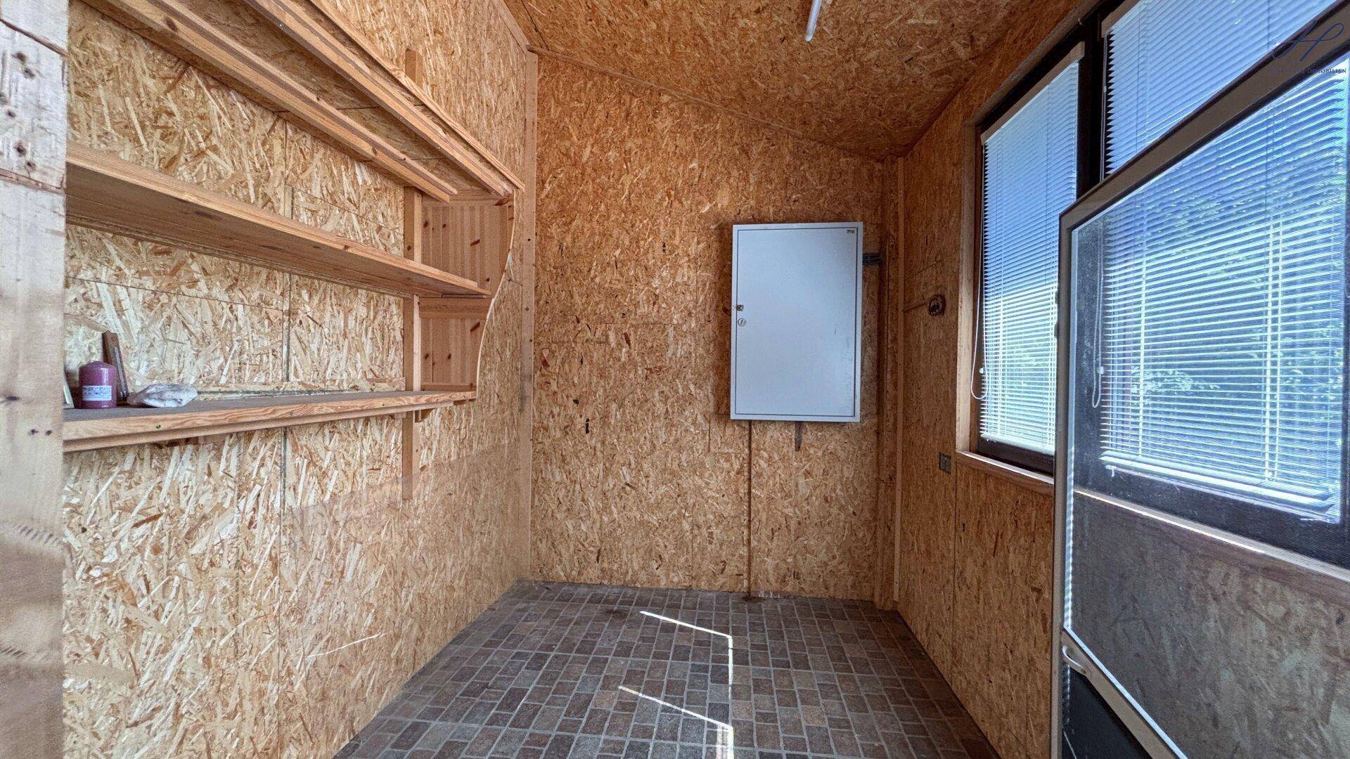 Abstellraum mit Holzplattenwänden und praktischen Regalen für zusätzlichen Stauraum.