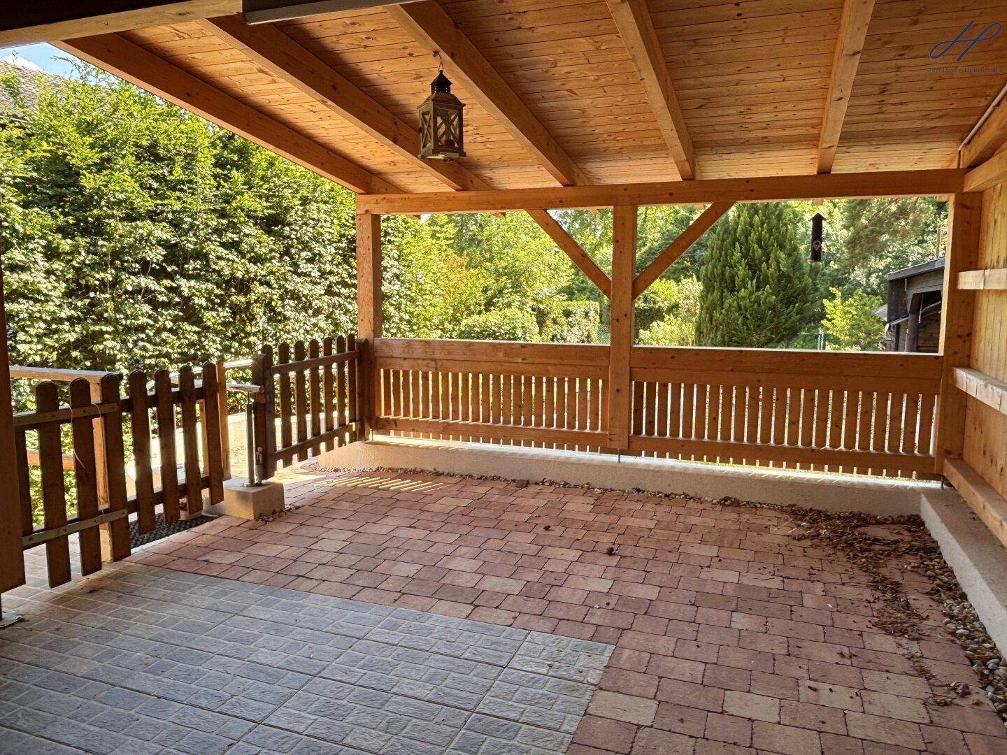 Überdachte Terrasse mit gepflastertem Boden und einer robusten Holzkonstruktion.