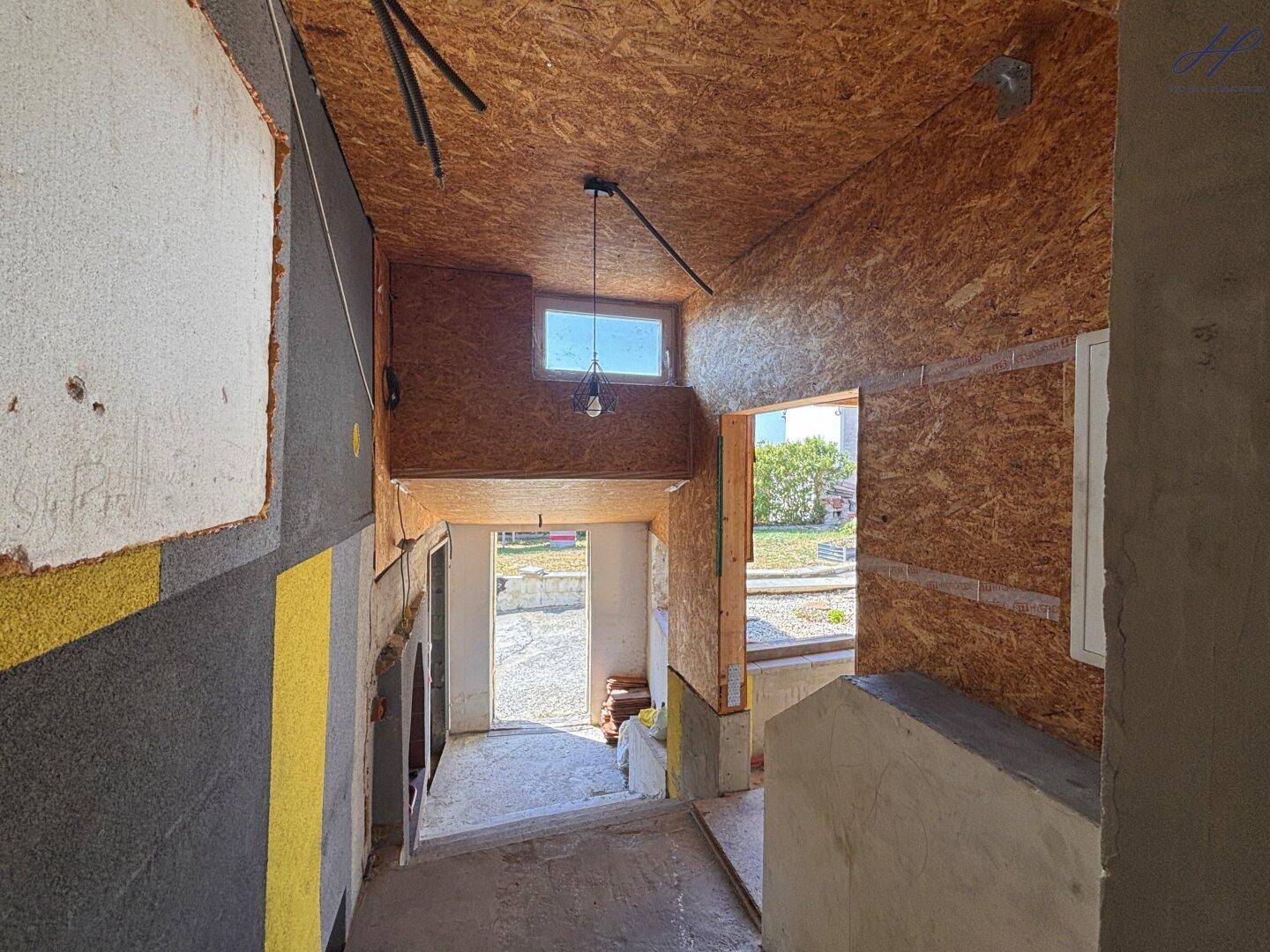 Innenansicht eines Flurs im Rohbau mit OSB-Platten an Wänden und Decke.
