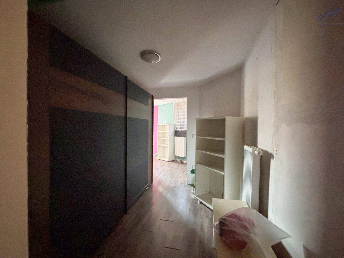 Flur mit großem Einbauschrank, Regalen und Zugang zu einem weiteren Zimmer.