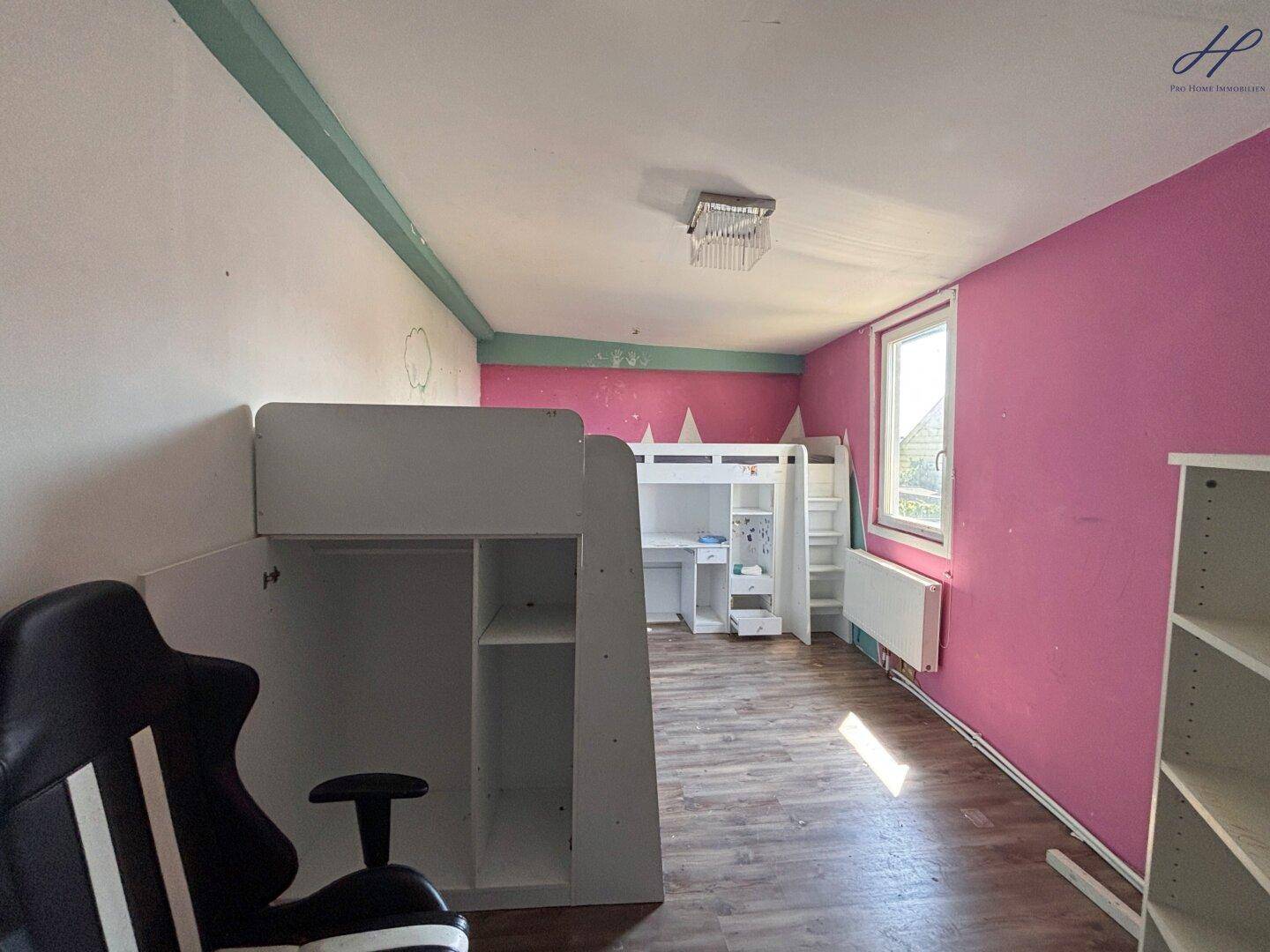 Kinderzimmer mit Etagenbett, Schreibtisch und auffälligen pinkfarbenen Wänden.