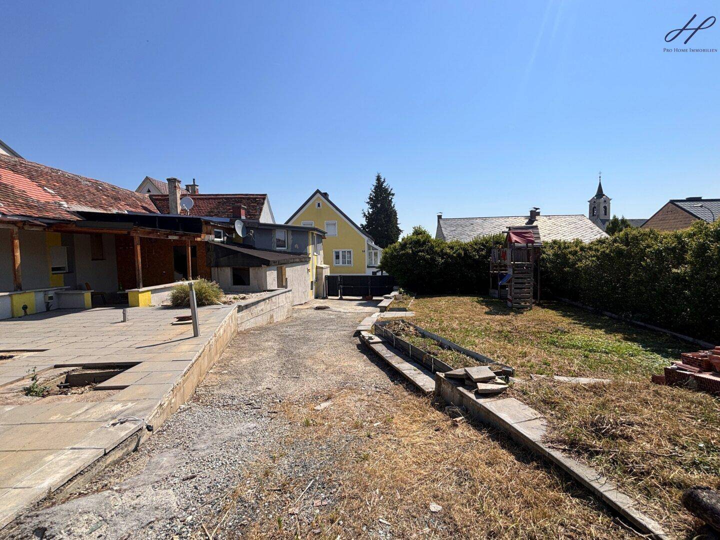 Großer Gartenbereich mit Spielplatz und Blick auf die umliegenden Häuser und die Kirche.