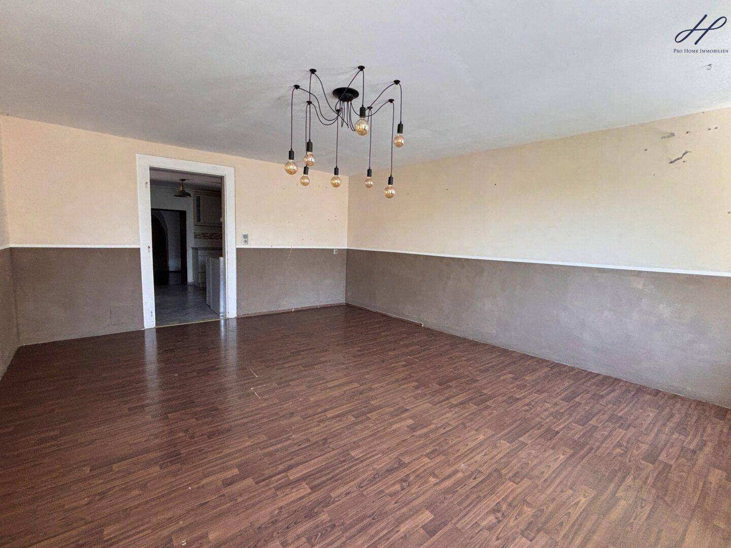 Geräumiger Essbereich mit Laminatboden, zweifarbiger Wandgestaltung und moderner Deckenleuchte.