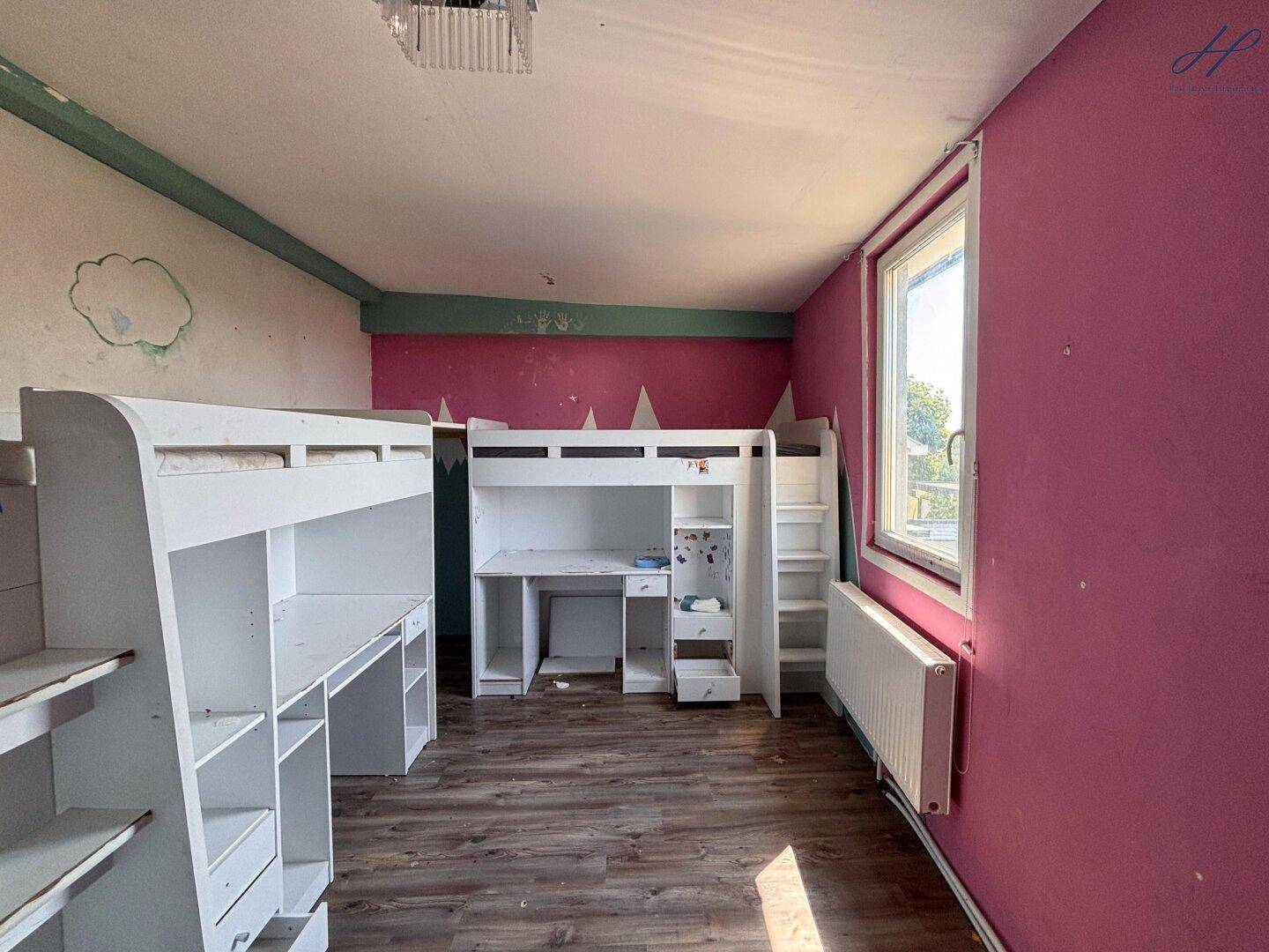 Helles Kinderzimmer mit Etagenbett, Schreibtisch und pinkfarbenen Wänden.