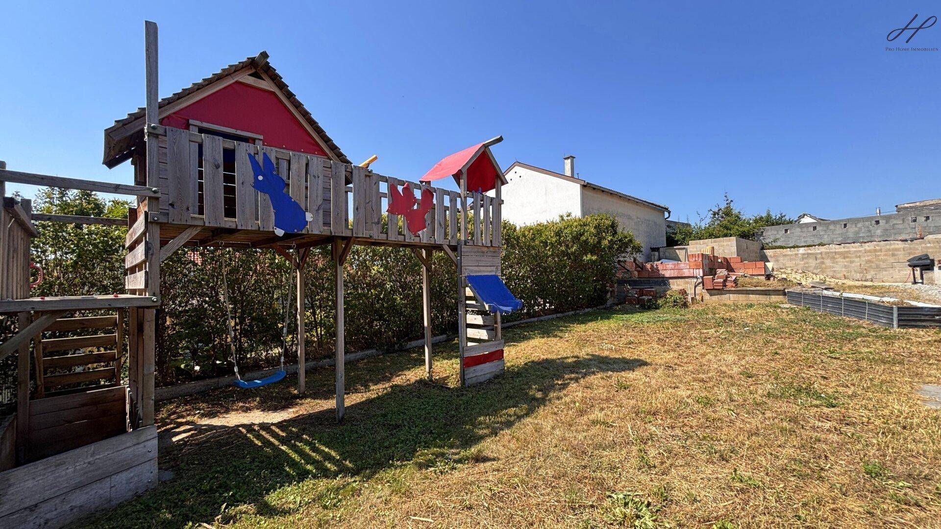 Detailansicht des Spielplatzes im Garten mit Schaukeln und einem kleinen Spielhaus.