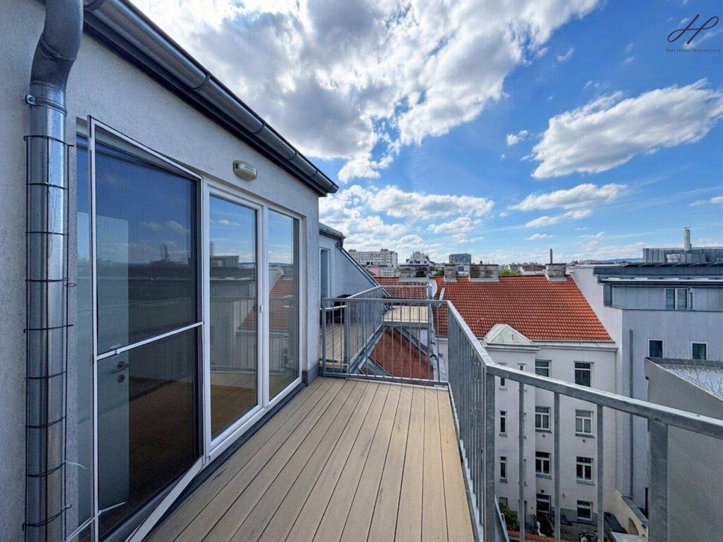 Helle Dachterrasse mit Zugang durch große Glasschiebetüren und Panoramablick über die Stadt.