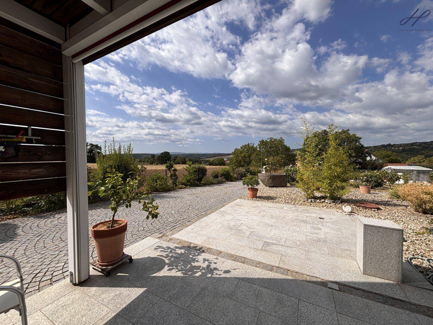 Große gepflasterte Terrasse mit Blick auf die Landschaft und den Garten.