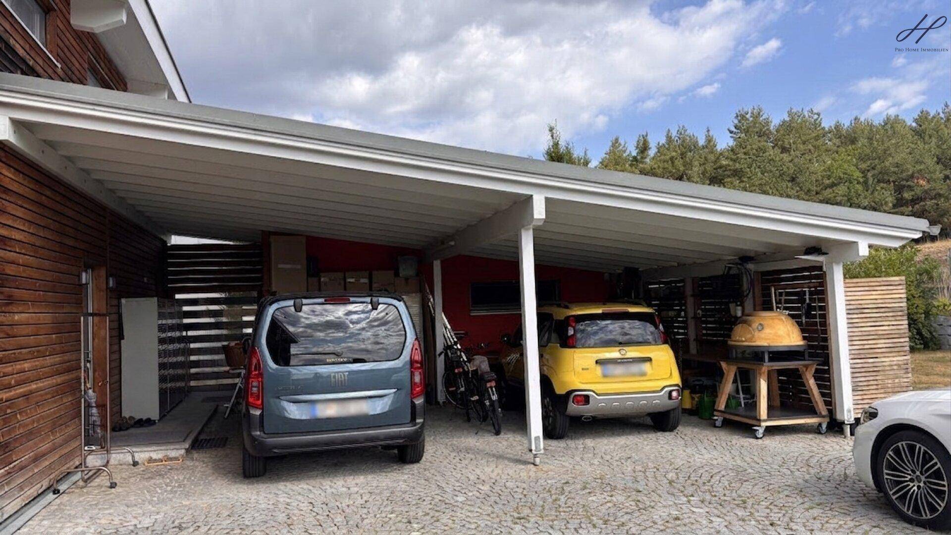 Überdachter Carport mit Platz für zwei Fahrzeuge und einem Grillbereich.