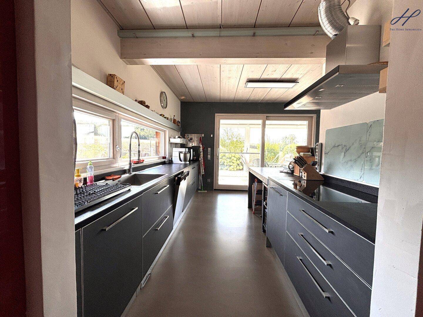 Moderne Küche mit dunklen Arbeitsplatten, Einbaugeräten und viel natürlichem Licht.
