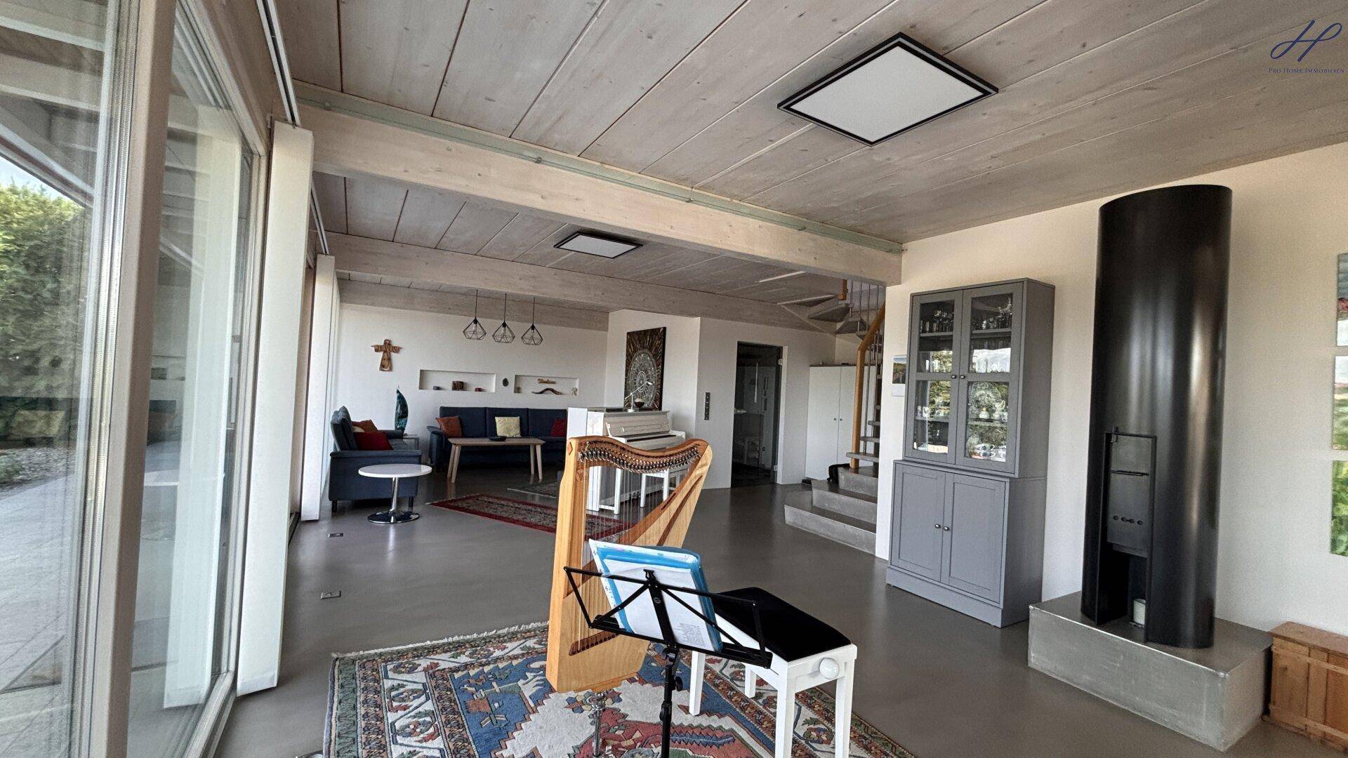Lichtdurchfluteter Wohnbereich mit Kaminofen, Klavier und Zugang zu den Außenbereichen.