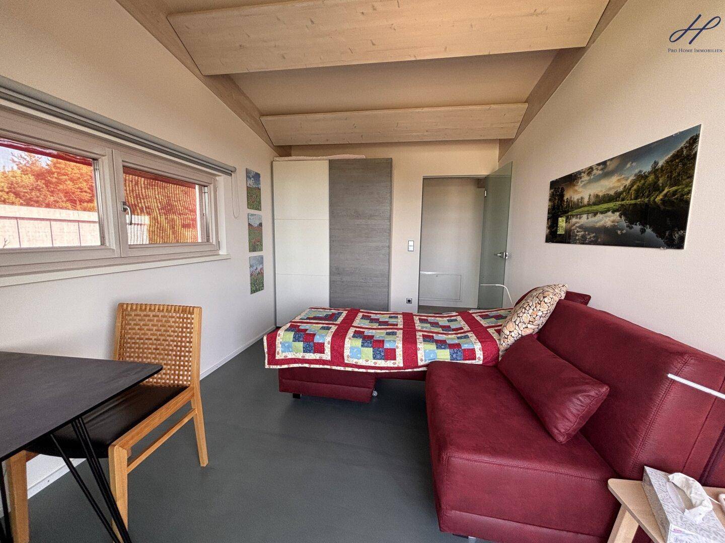 Helles Schlafzimmer mit Doppelbett, Kleiderschrank und Blick auf die umliegende Landschaft.
