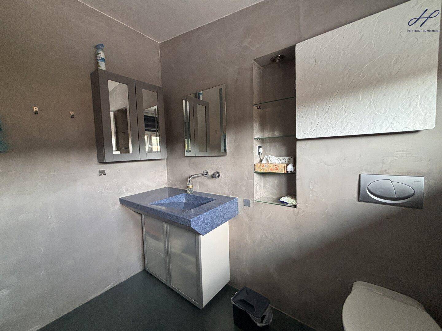 Badezimmer mit modernem Waschbecken, Spiegelschrank und Wand-WC.