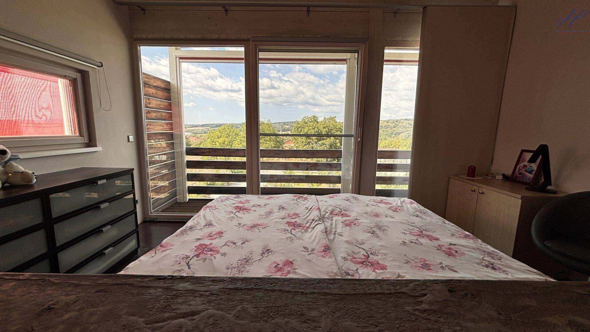 Schlafzimmer mit Panoramablick durch große Fenster und Balkonzugang.